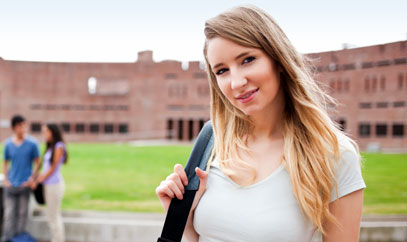 Junge Frau mit Umhängetasche vor einem Universitätsgebäude.
